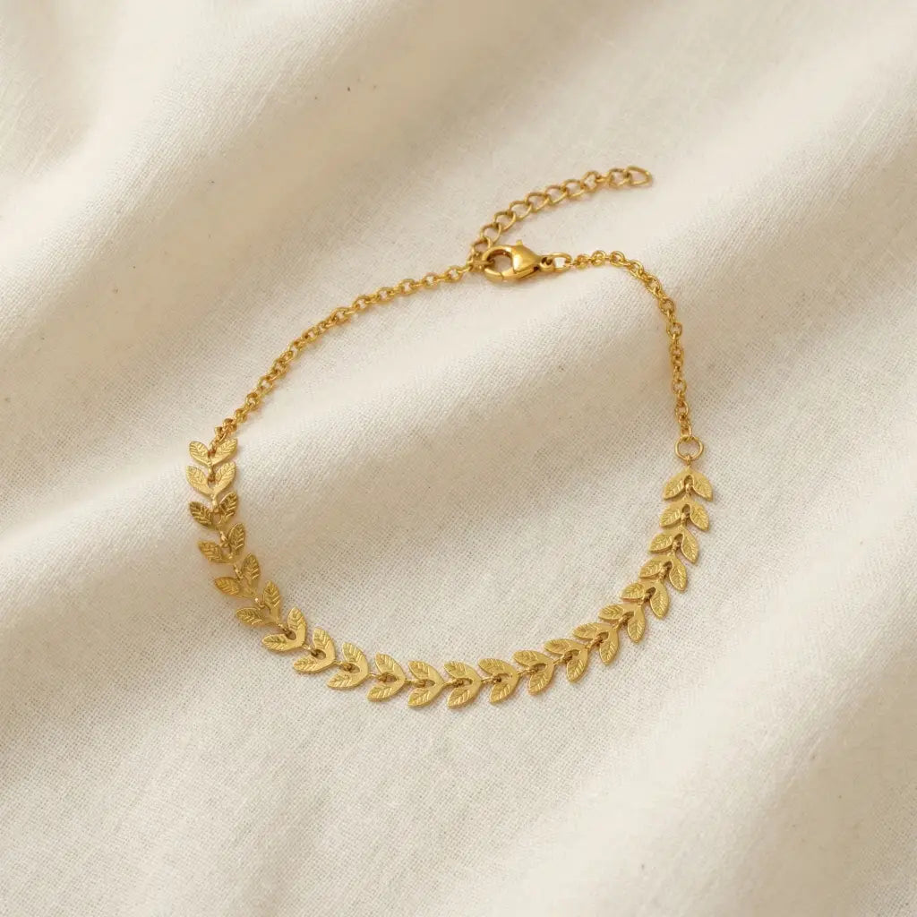 Gold necklace with leaf design on a beige fabric background