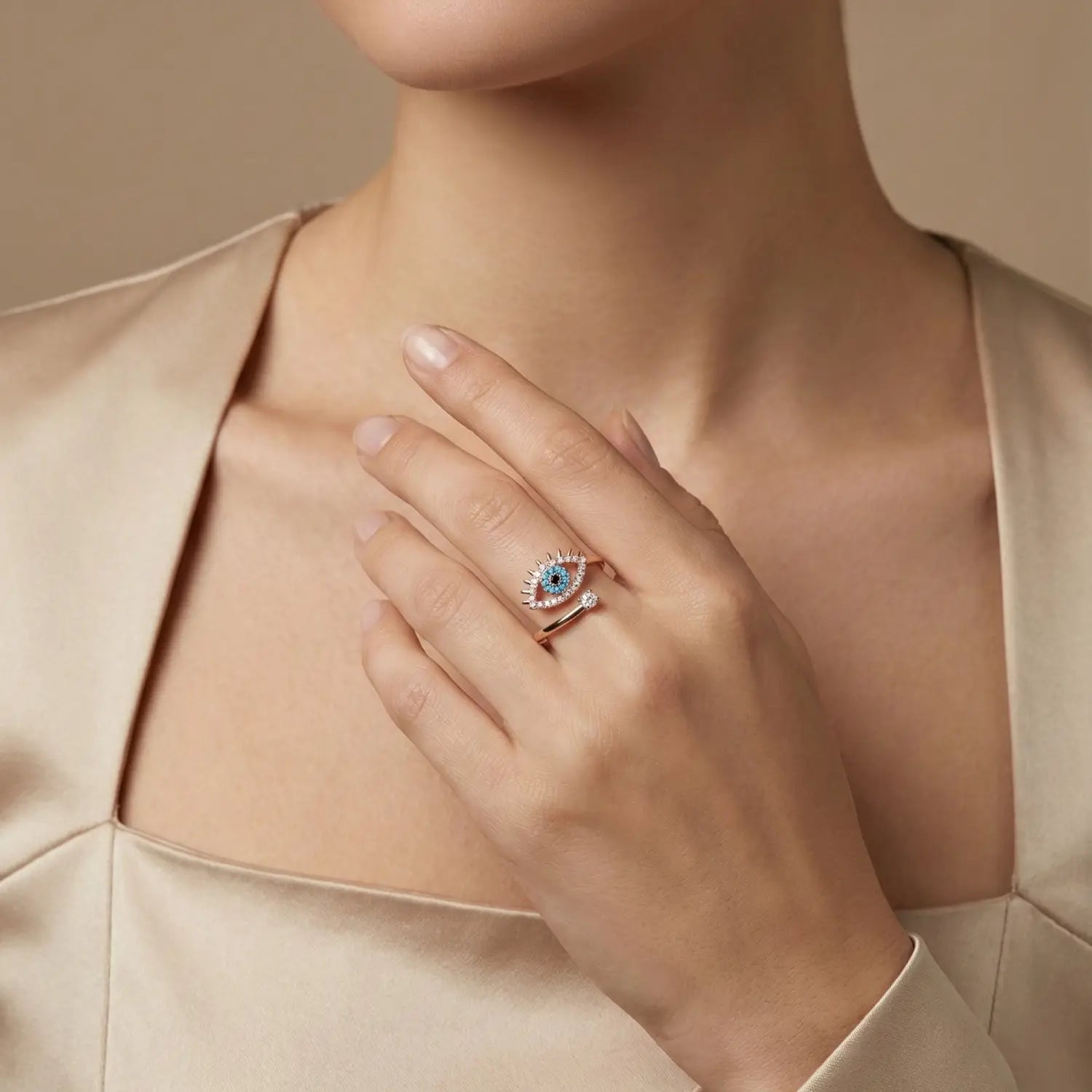 Close-up of a hand wearing a ring with a evil eye ring, set against a neutral background.