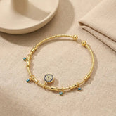 Golden charm bracelet with evil eye details on fabric