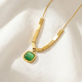 Gold necklace with a green pendant on a white fabric background