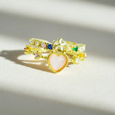 Set of gold rings with heart and flower designs on a light background