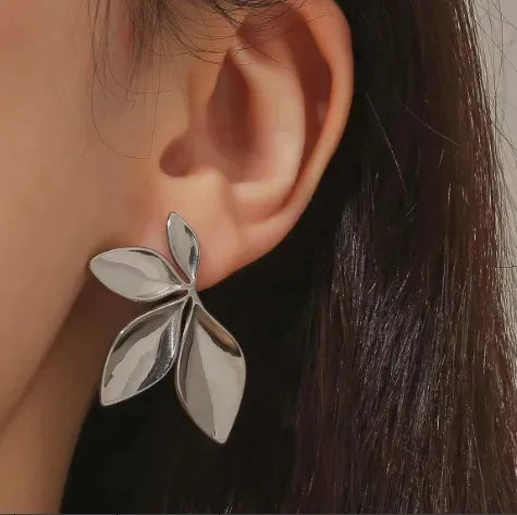 Silver leaf-shaped earring worn by a person with dark hair.