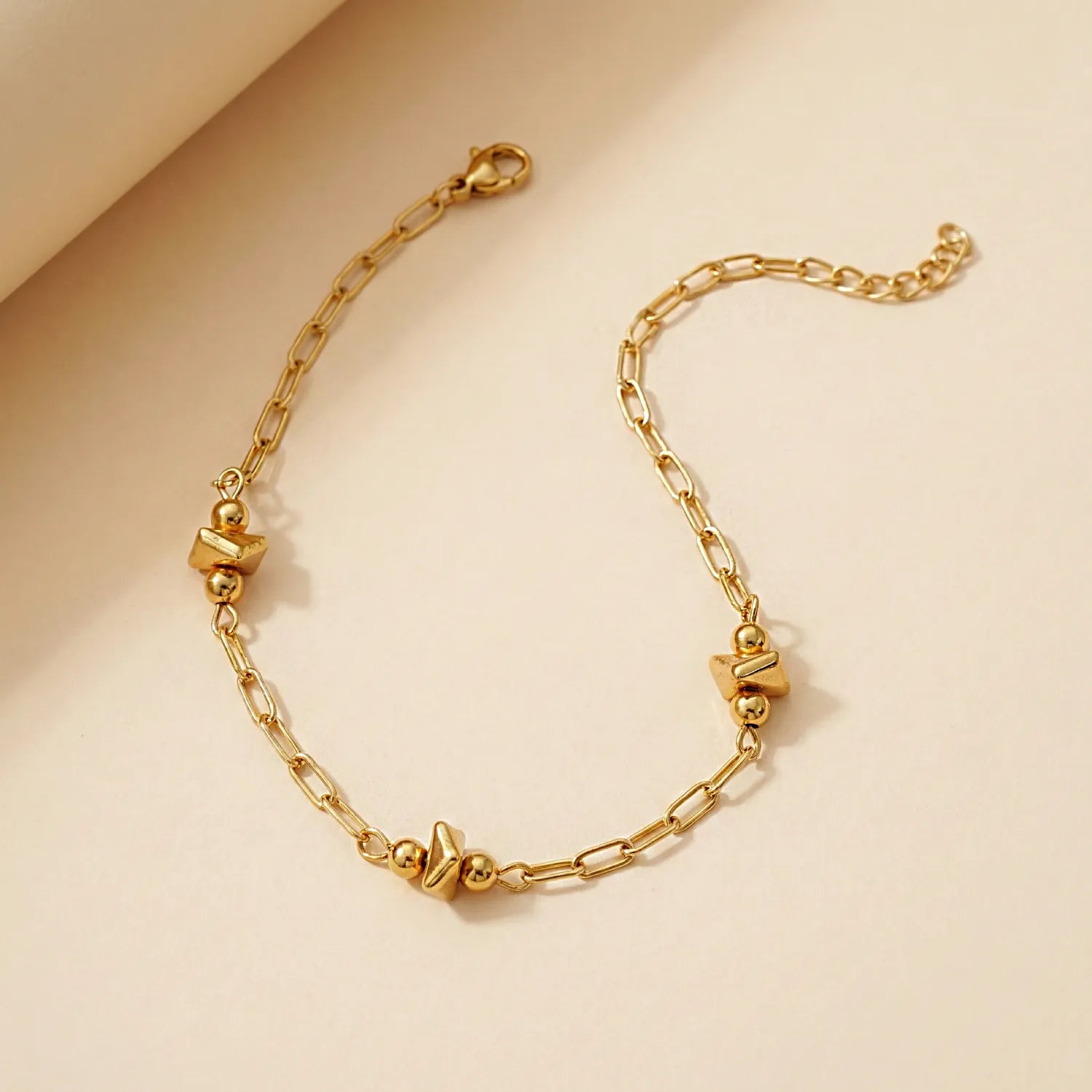 Gold bracelet with heart-shaped beads on a beige background