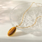 Gold necklace with a tiger's eye stone pendant on a white background
