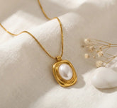 Gold necklace with a pearl pendant on a soft white background