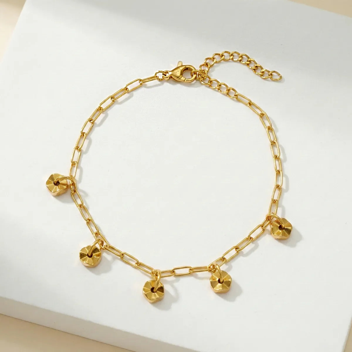 Gold chain bracelet with heart-shaped charms on a white background