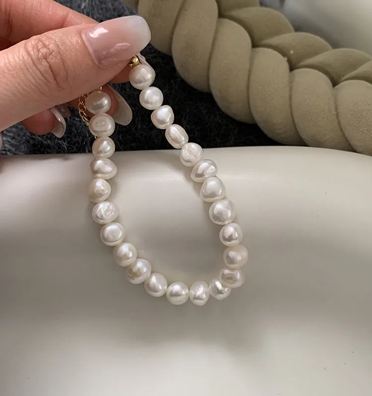Pearl bracelet held by a hand on a neutral background