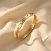 Gold ring with embedded gemstones on a beige fabric background