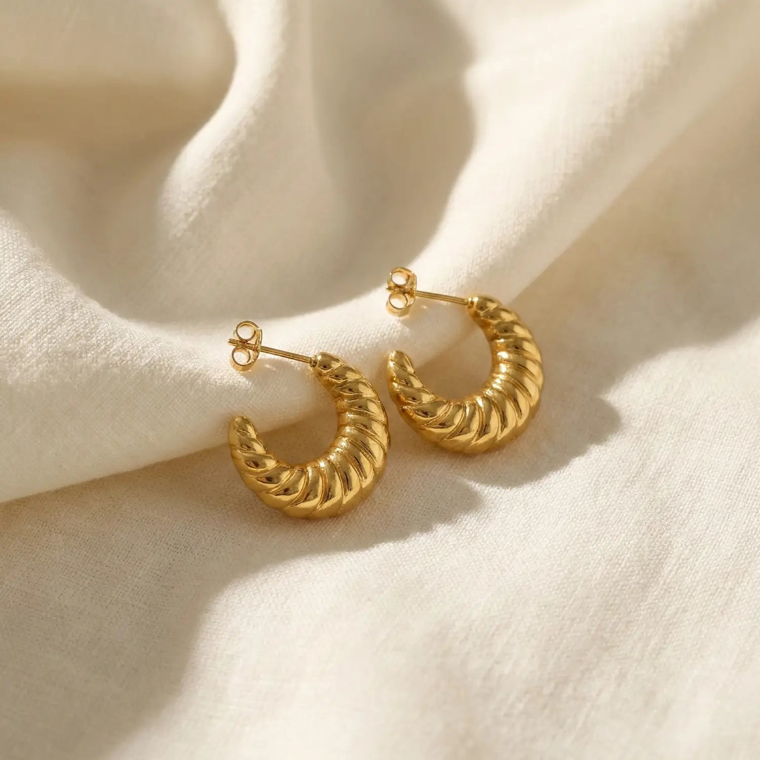 Gold hoop earrings on a beige fabric background