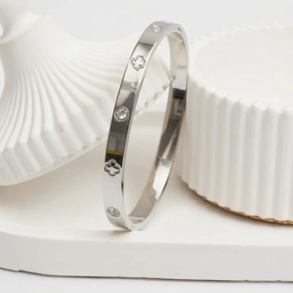 Silver bracelet with engraved designs on a white shell background