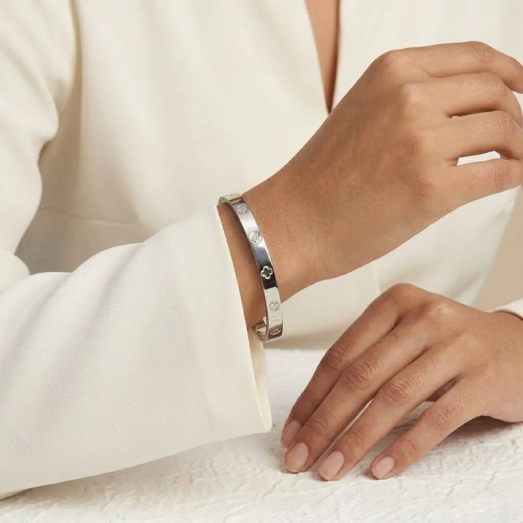 Silver bracelet on a person's wrist with a neutral background