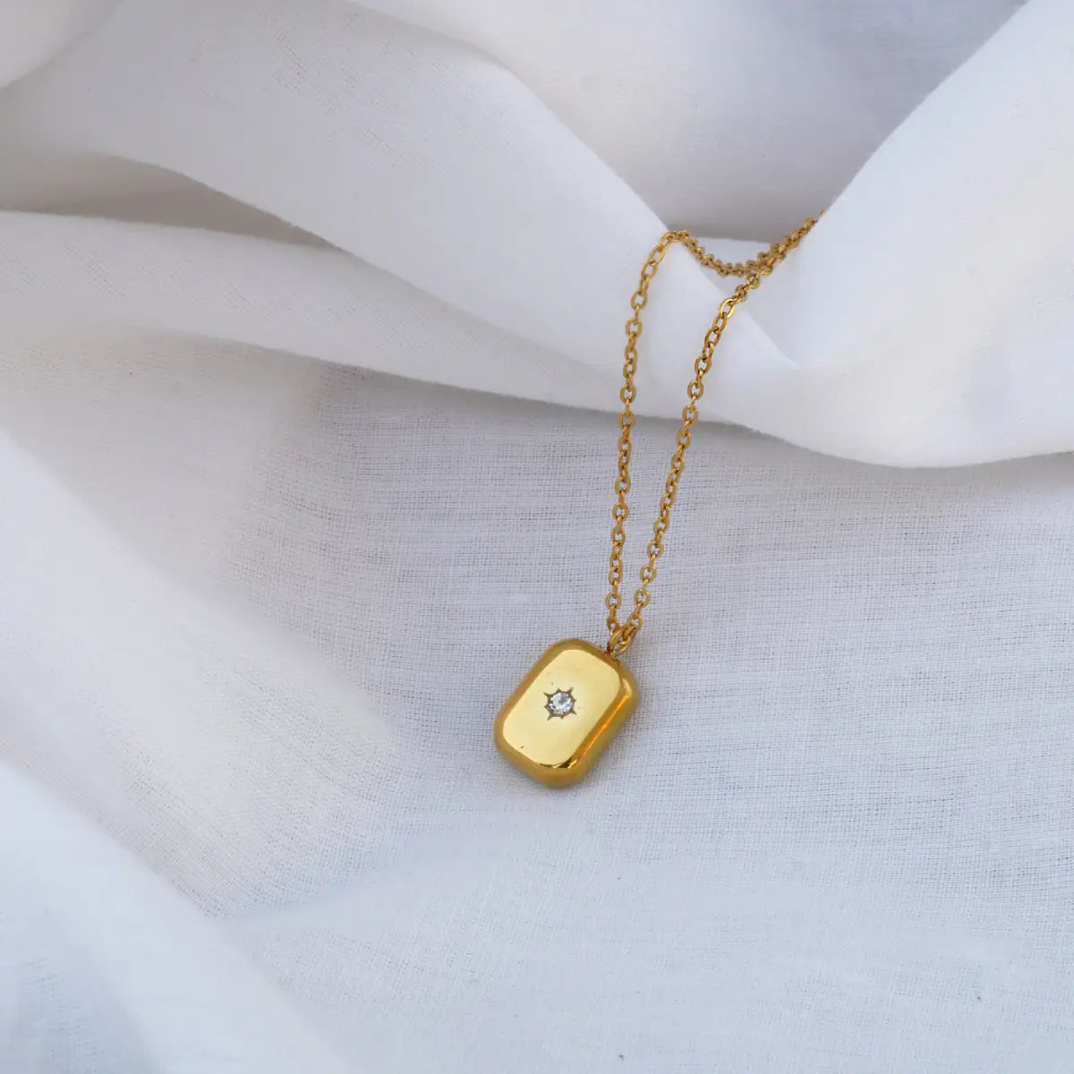 Gold necklace with a pendant on a white fabric background