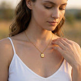 Woman wearing a gold necklace with a pendant in a natural setting