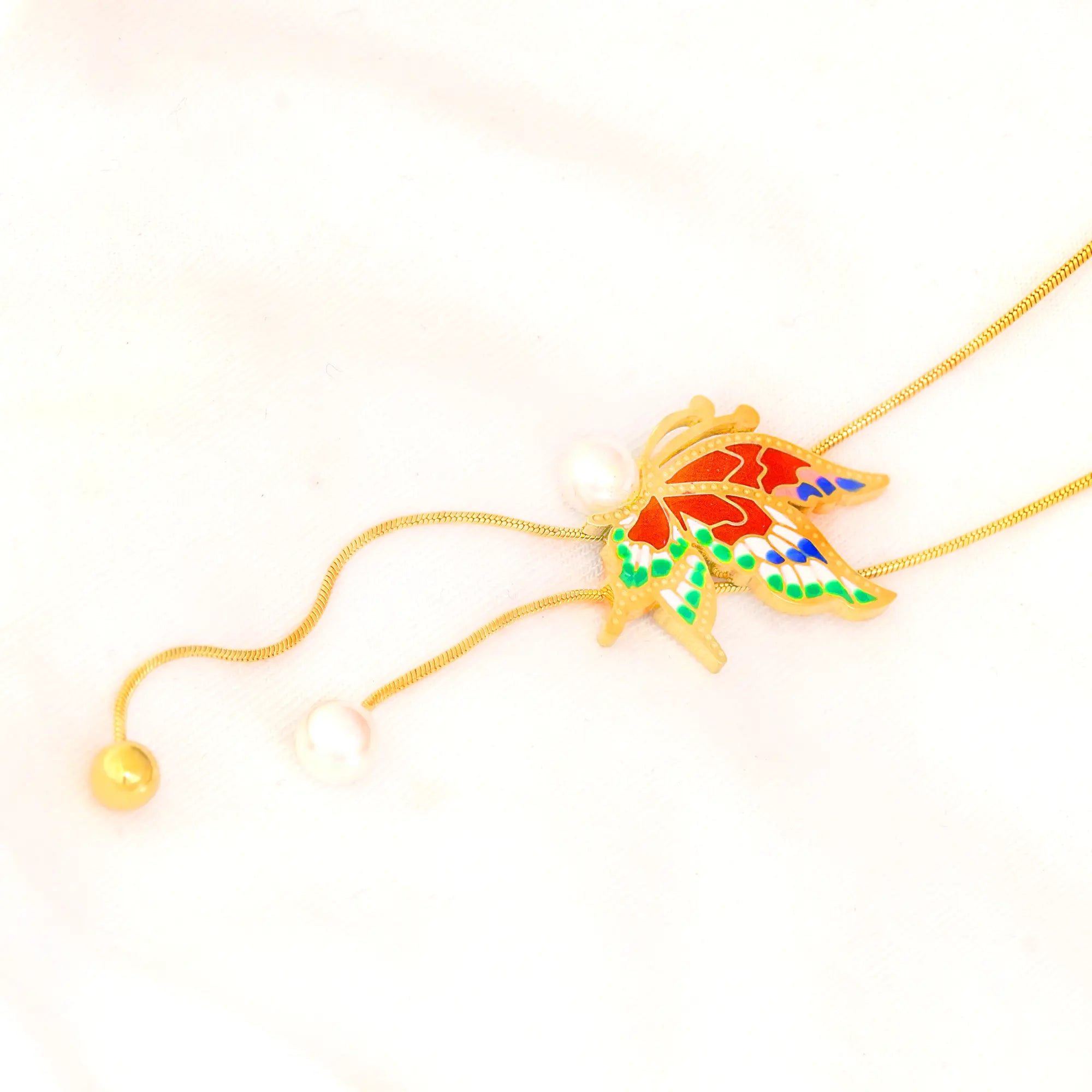 Colorful fish pendant on a gold chain against a white background