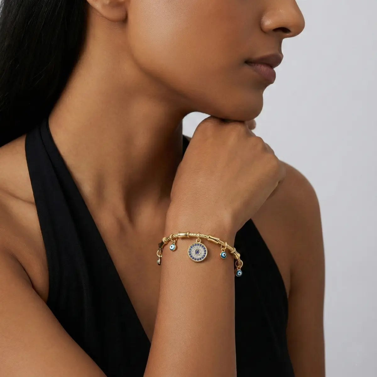 Woman wearing a gold bracelet with a neutral background