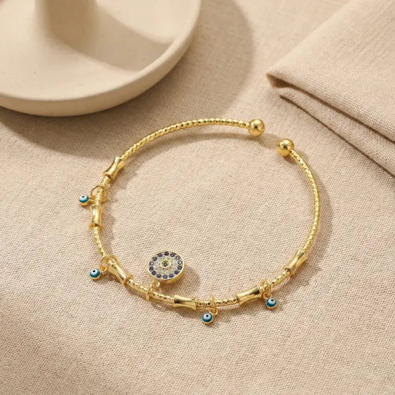 Golden charm bracelet with evil eye details on fabric