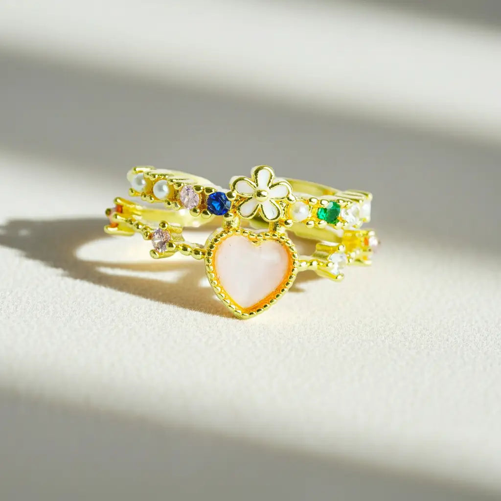 Set of gold rings with heart and flower designs on a light background