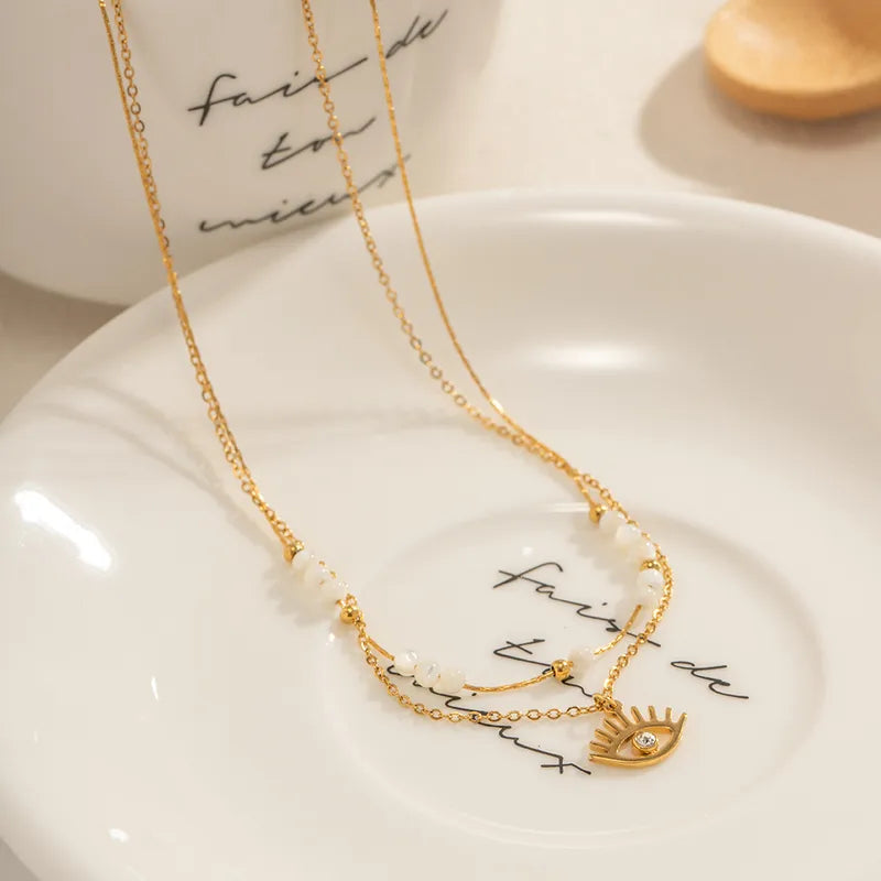 Gold necklace with eye-shaped pendant on a white dish