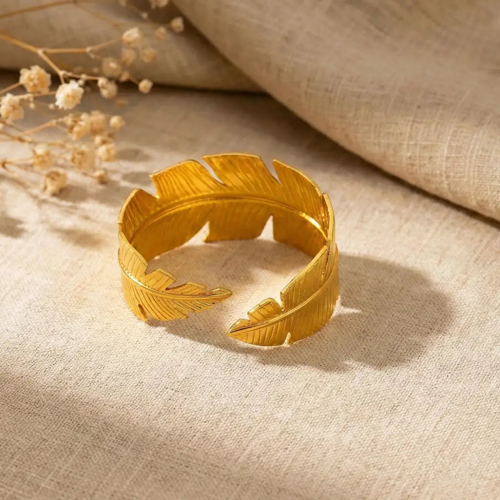 Gold leaf-shaped bracelet on a textured beige fabric background