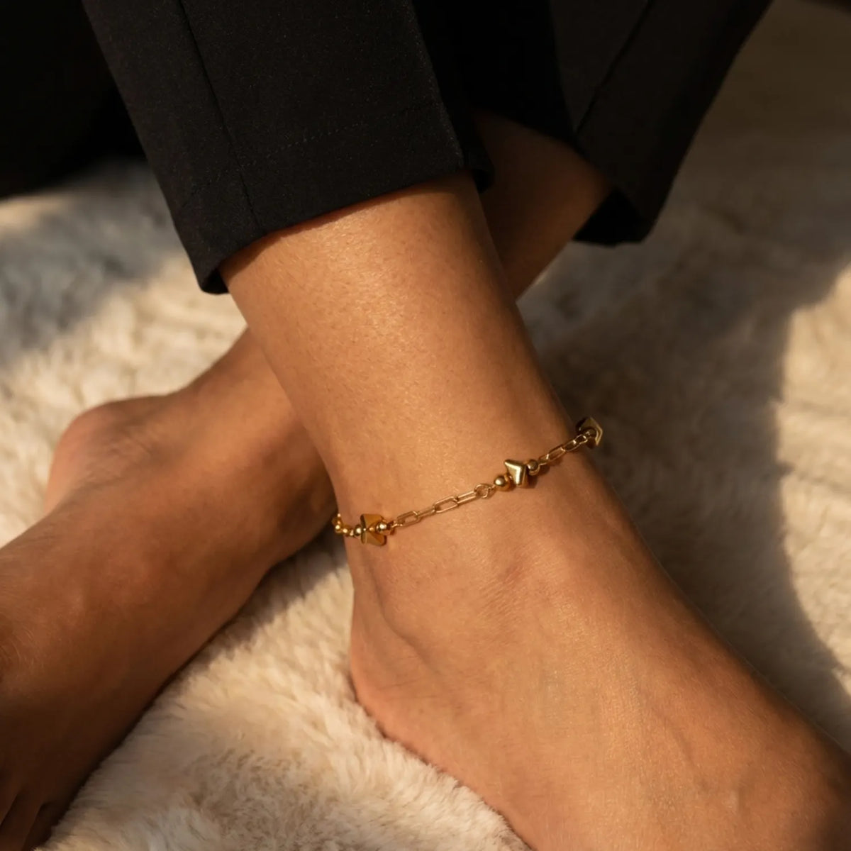 Gold anklet on a person's ankle with a blurred background