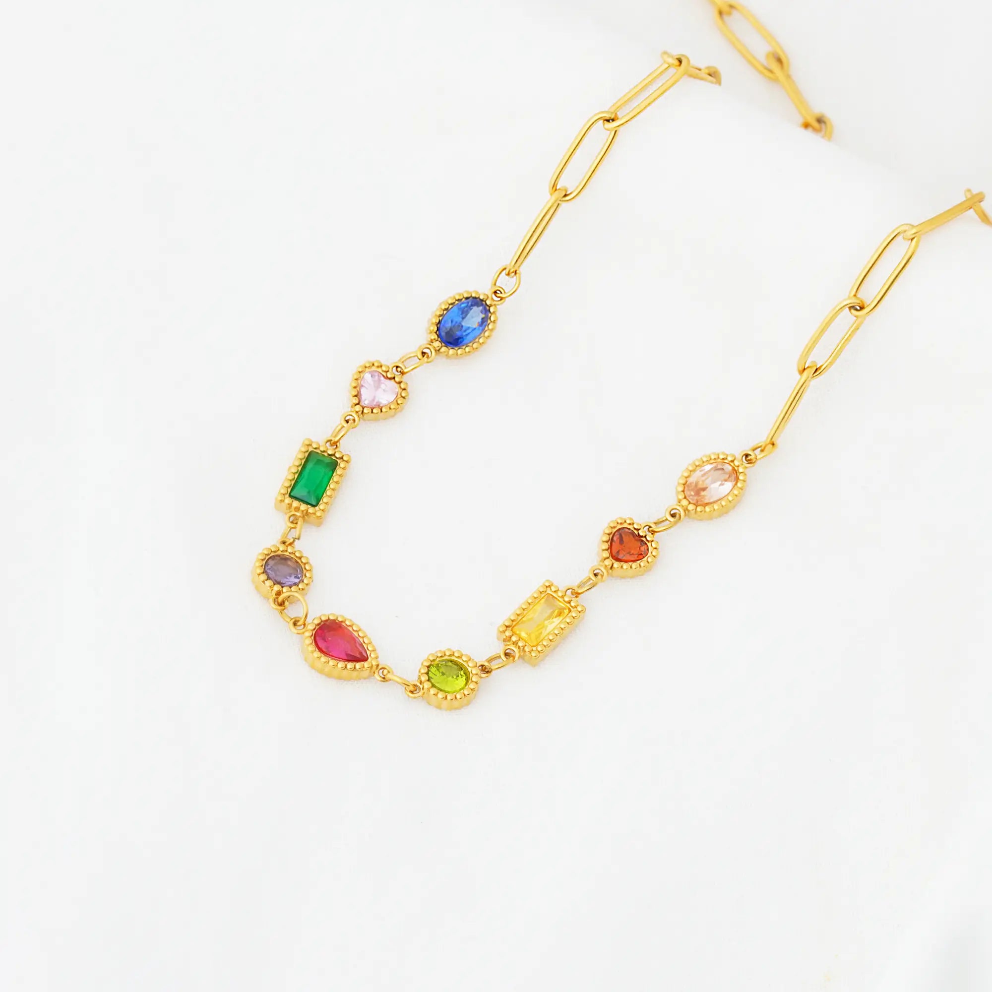 Gold necklace with colorful gemstones on a white background
