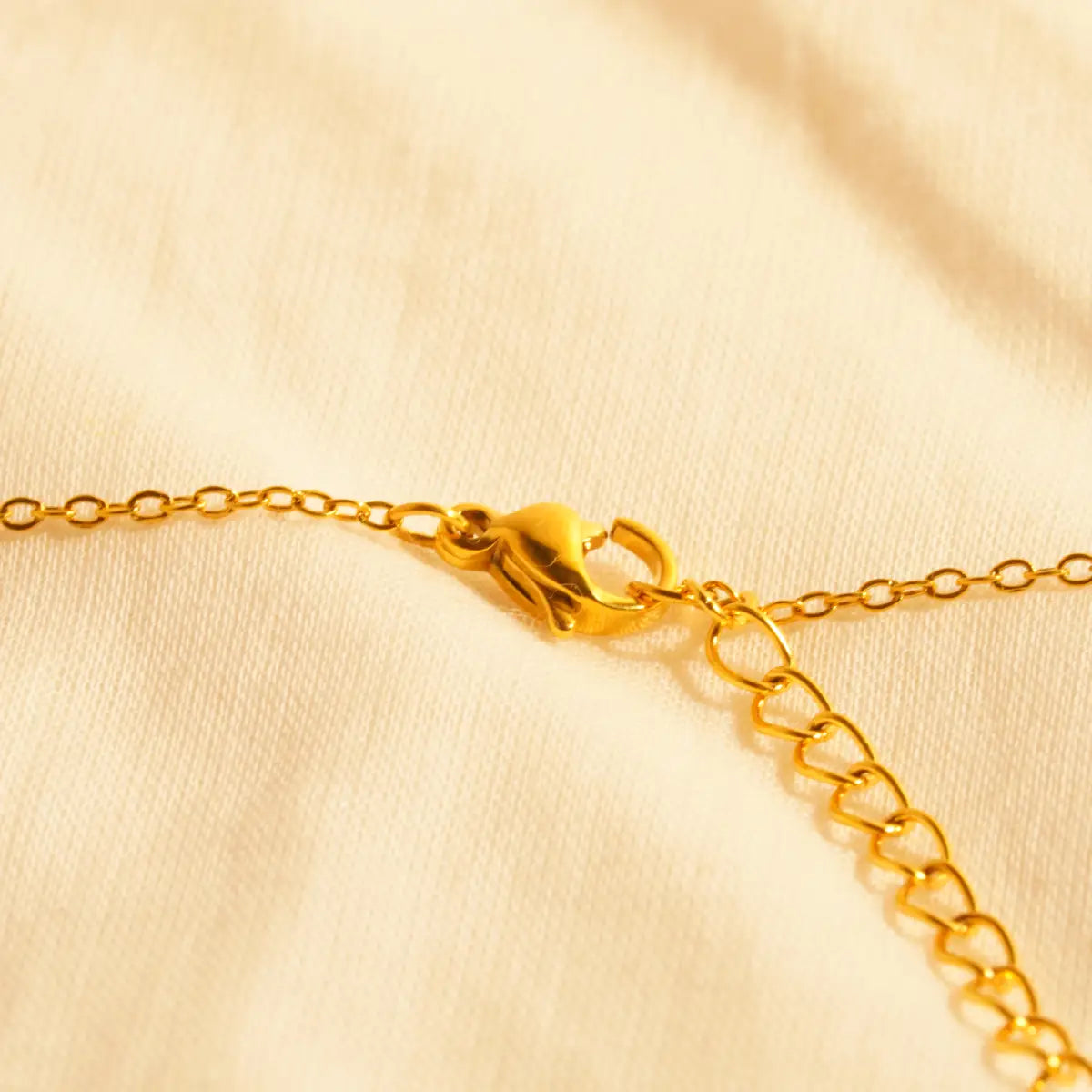 Gold chain bracelet on a beige fabric background