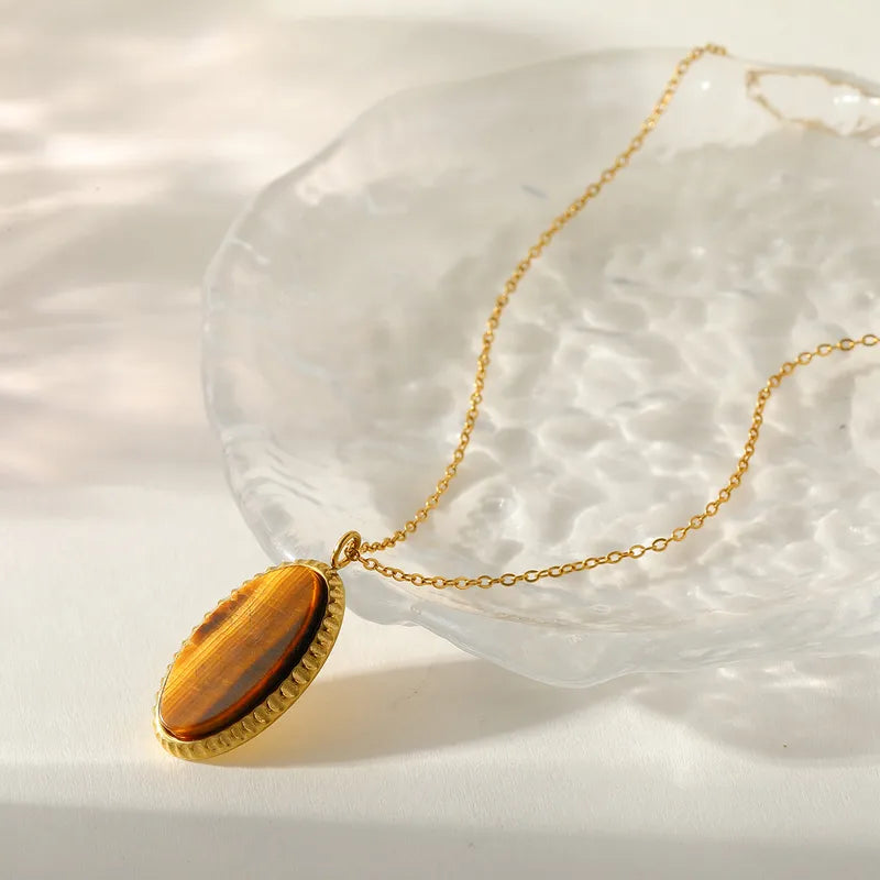 Gold necklace with a tiger's eye stone pendant on a white background