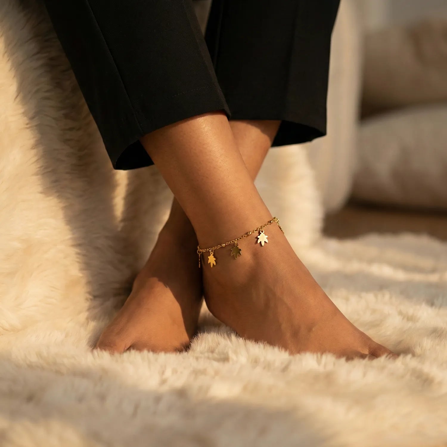 Close-up of feet with anklets on a soft surface