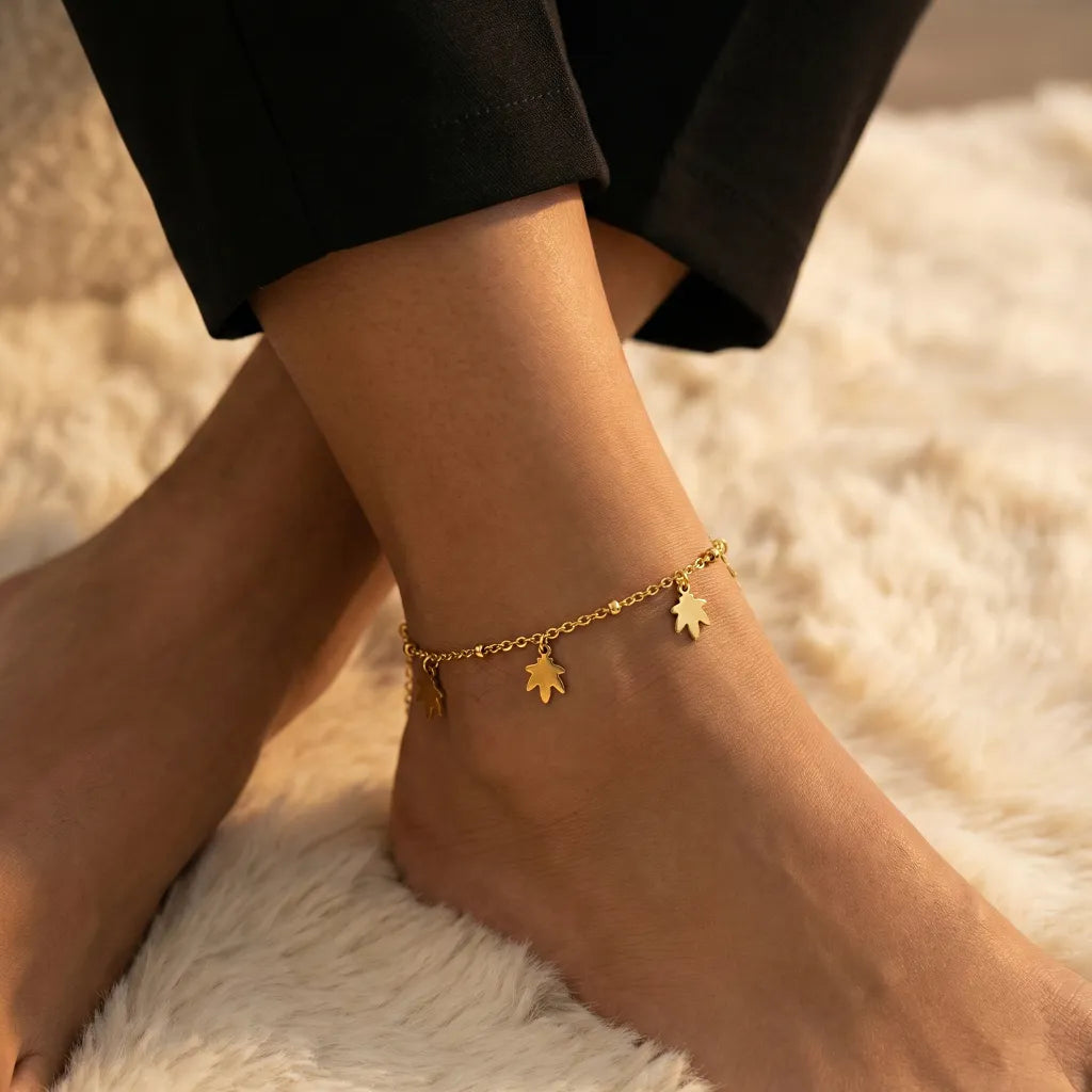 Gold anklet with charms on a person's ankle against a blurred background