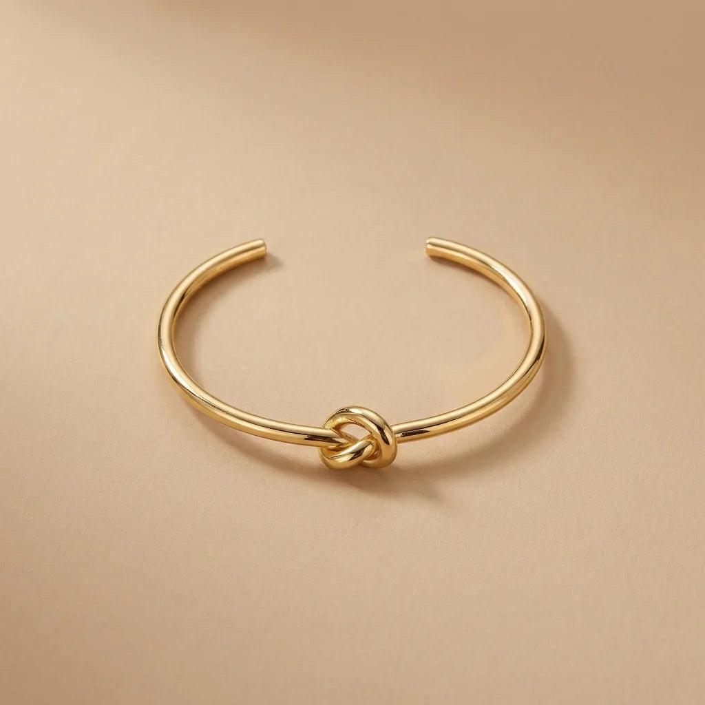 Gold knot bangle on a beige background