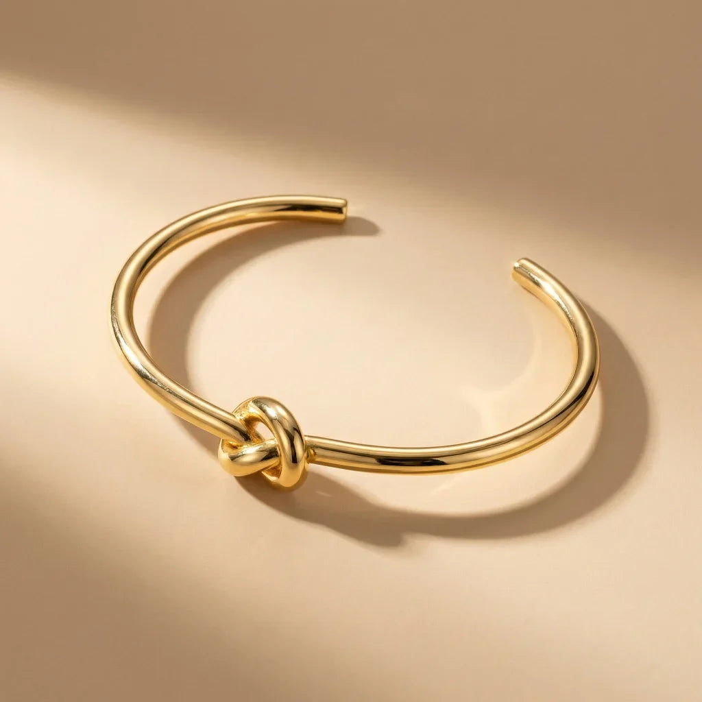 Gold bracelet with knot design on a beige background