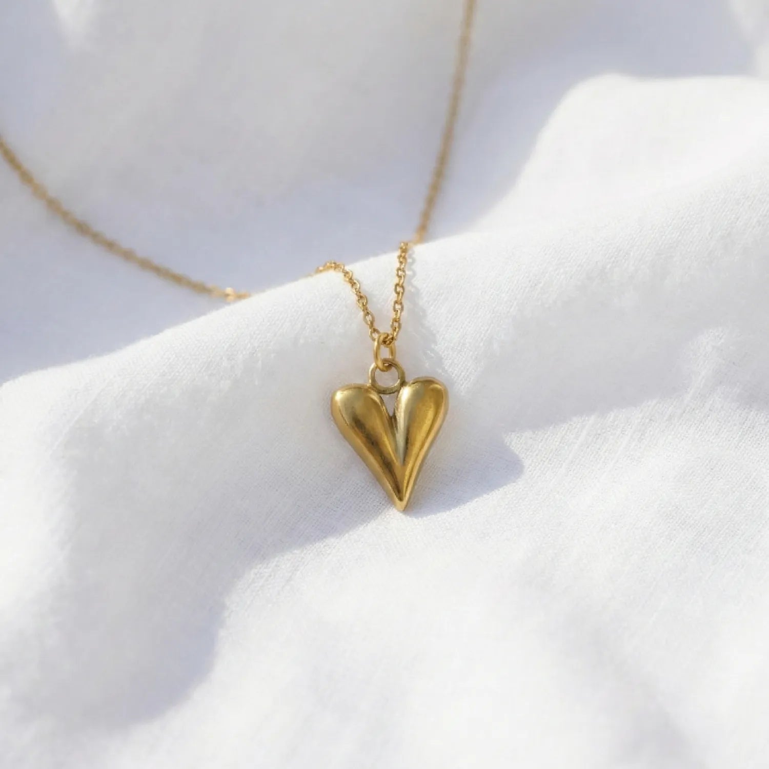Gold heart-shaped necklace on a white surface