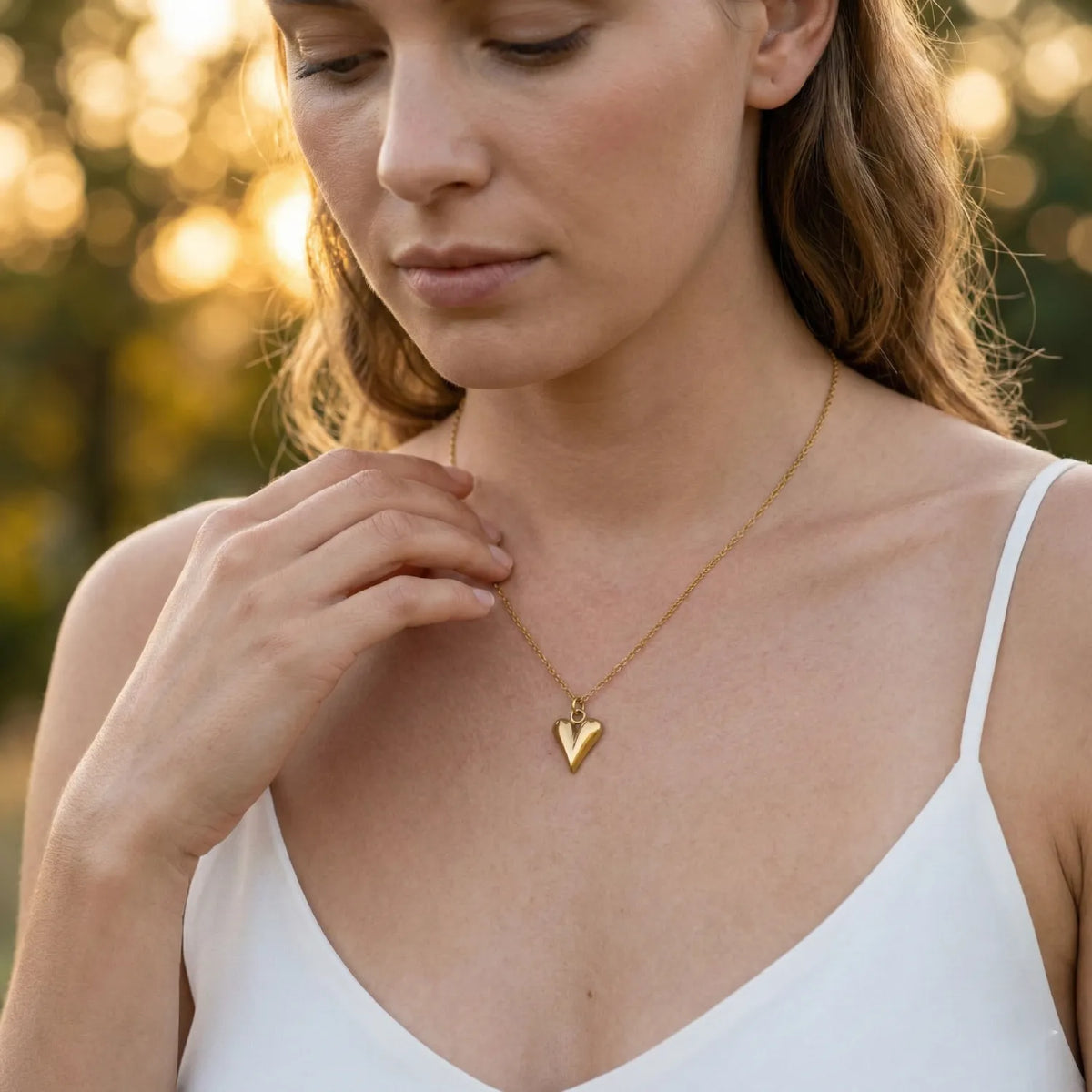 Woman wearing a gold necklace with a heart pendant outdoors