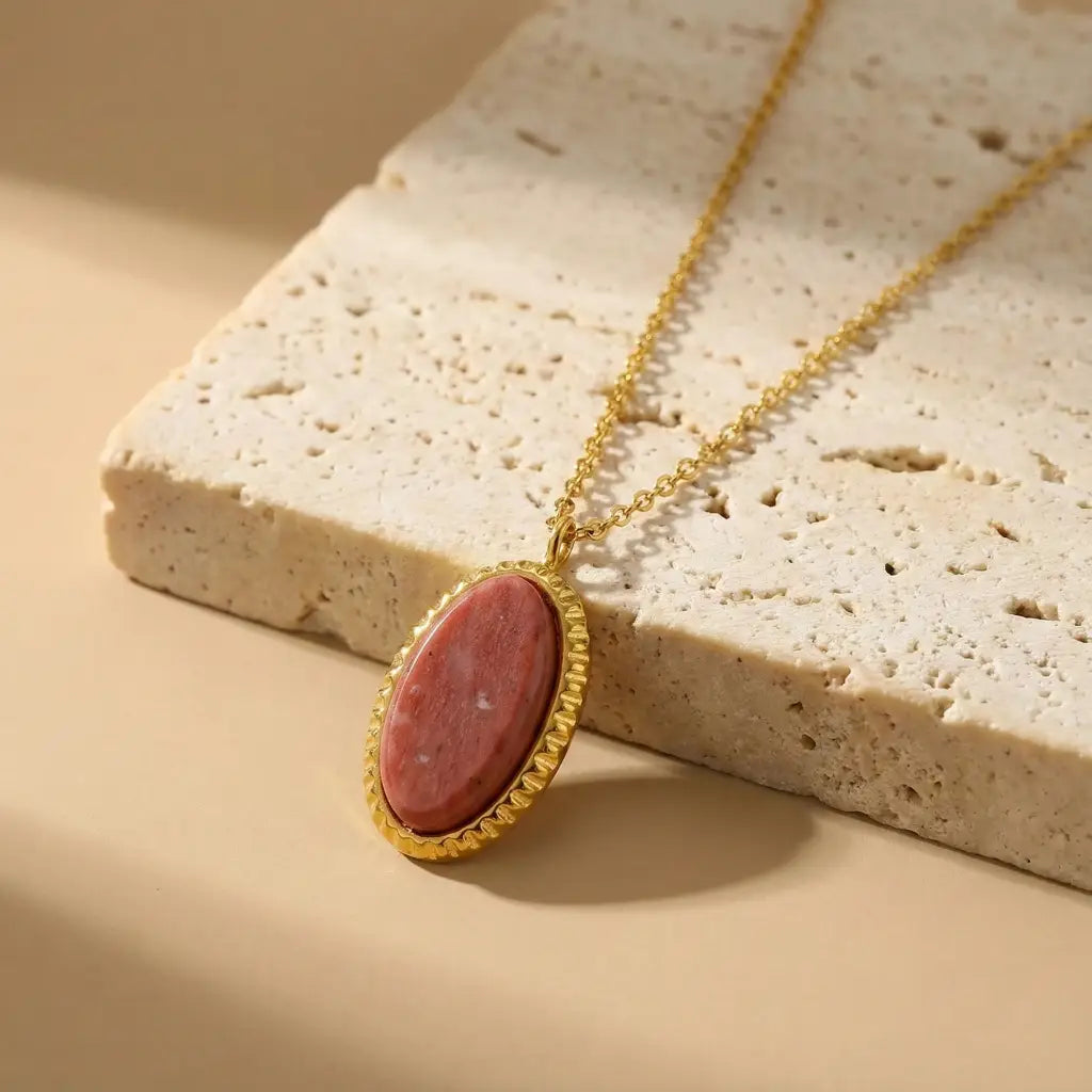 Necklace with a red stone pendant on a textured beige surface