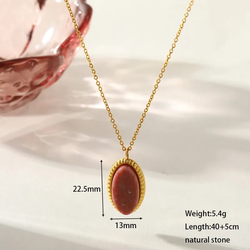 Gold necklace with a red stone pendant on a white background