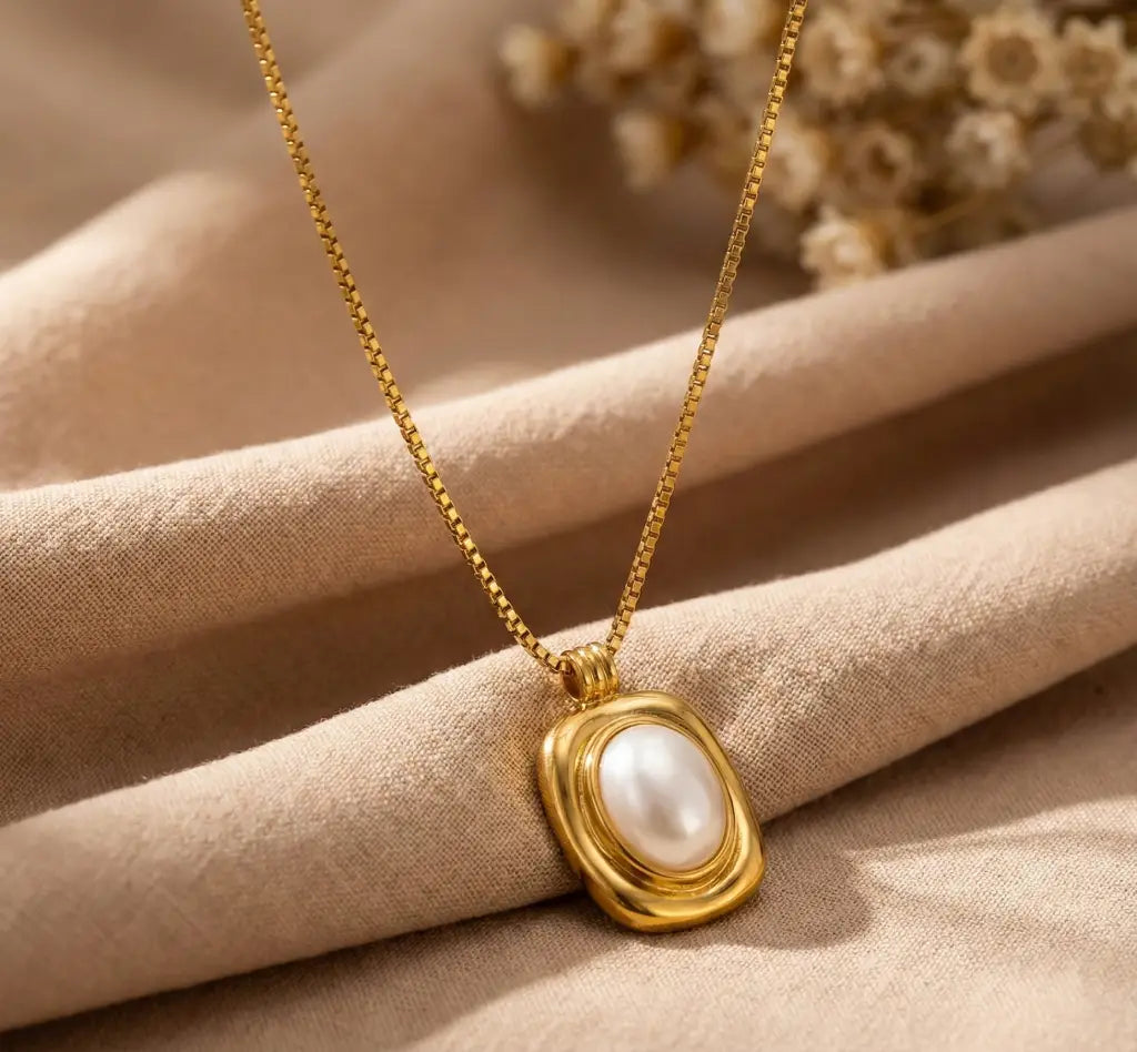 Gold necklace with a pearl pendant on beige fabric