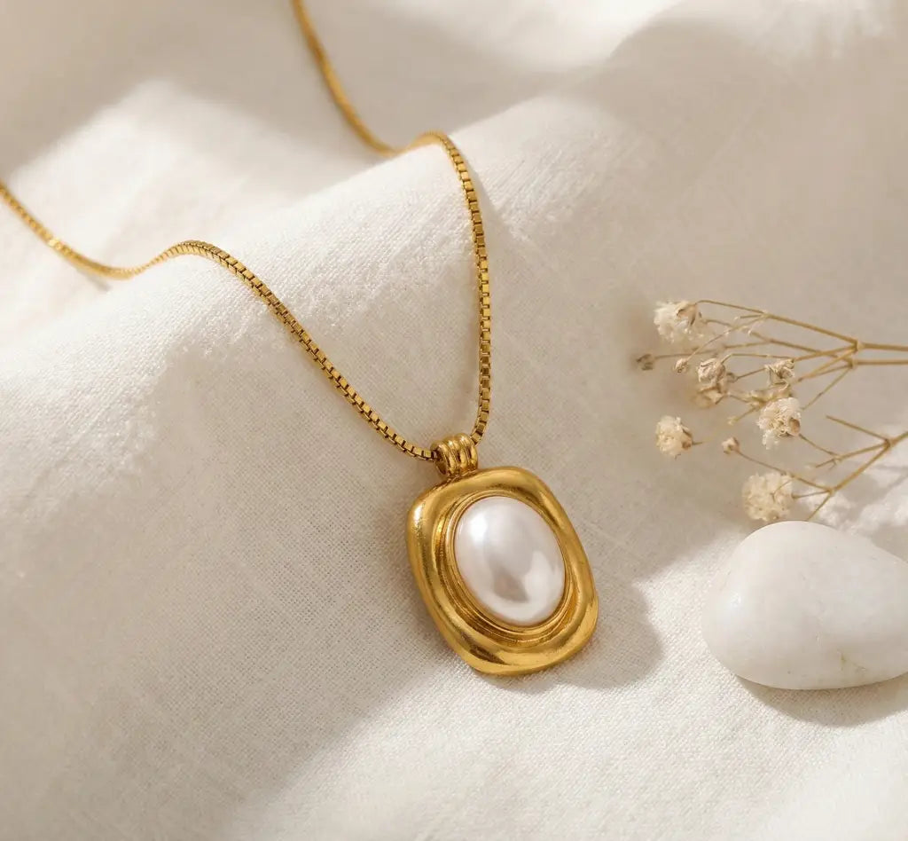 Gold necklace with a pearl pendant on a soft white background