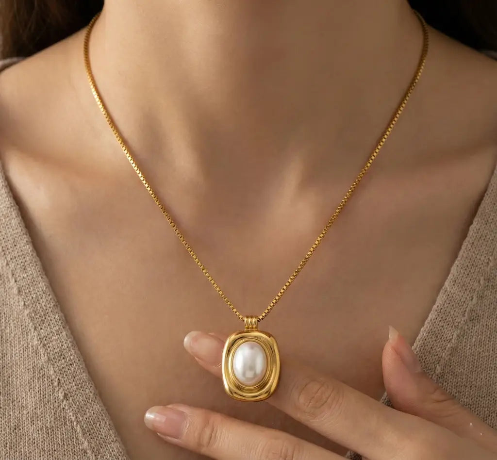 Gold necklace with a pearl pendant worn by a person
