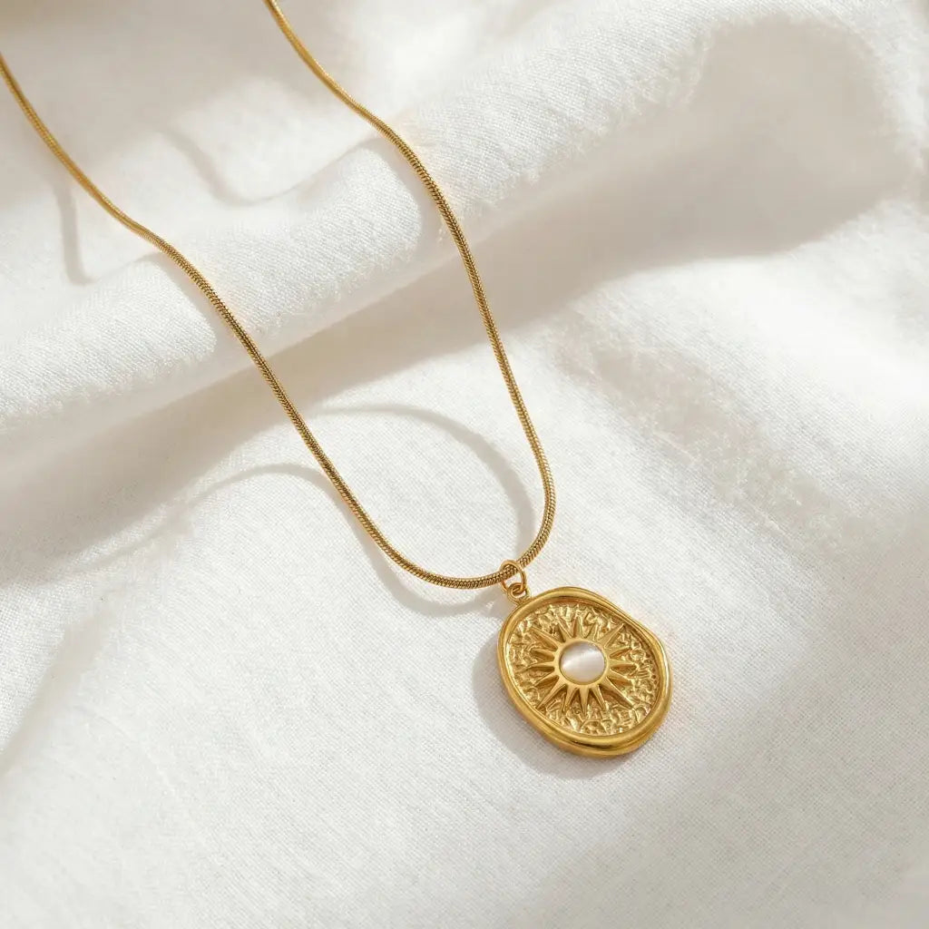 Gold necklace with a decorative pendant on a white fabric background