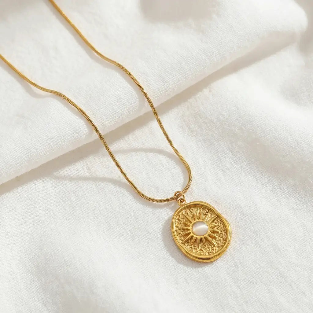 Gold necklace with a decorative pendant on a white fabric background