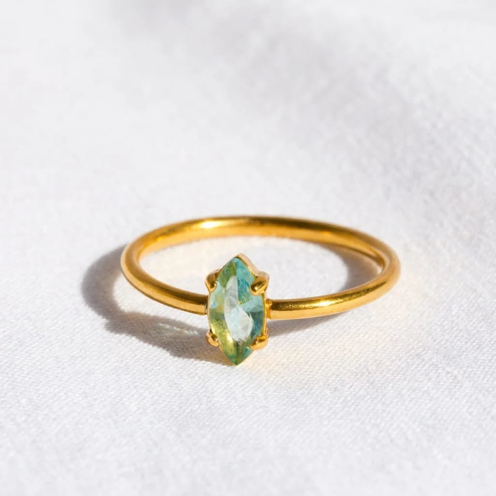 Gold ring with a green gemstone on a white background