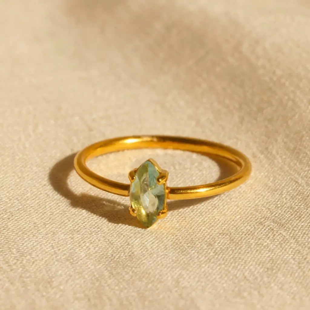 Gold ring with a green gemstone on a beige fabric background
