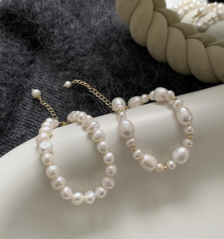 Pearl hoop earrings on a hand with a blurred background