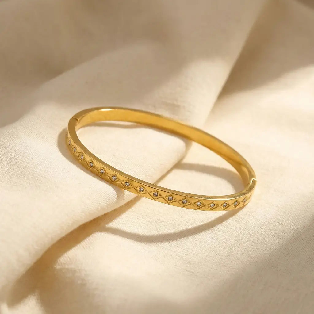 Gold bracelet with small stones on a beige fabric background