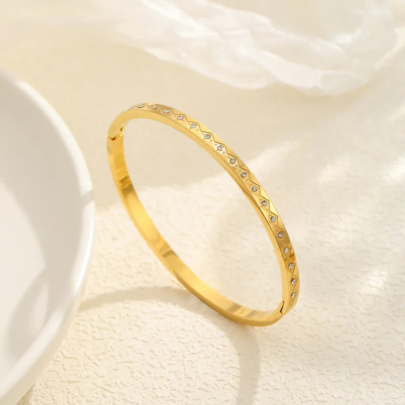 Gold bracelet with small stones on a light beige background