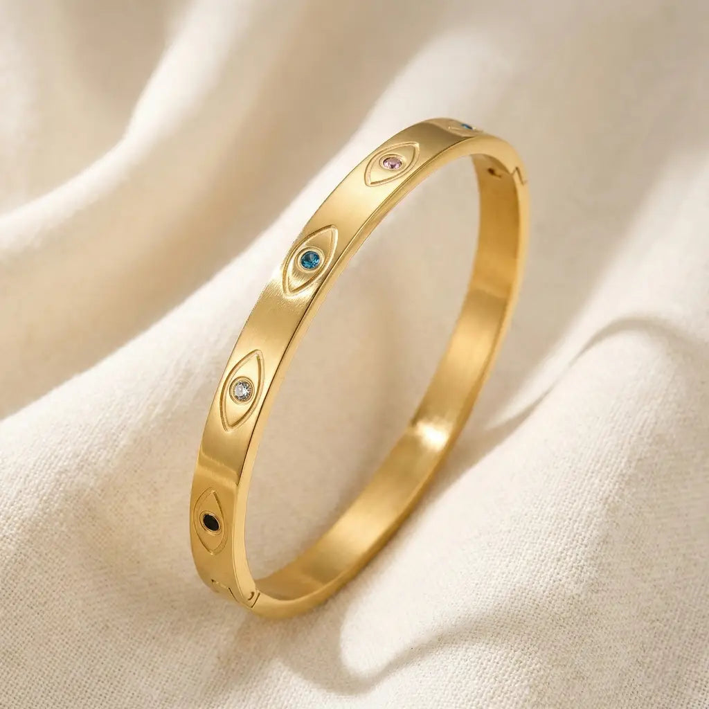 Gold bracelet with embedded stones on a beige fabric background