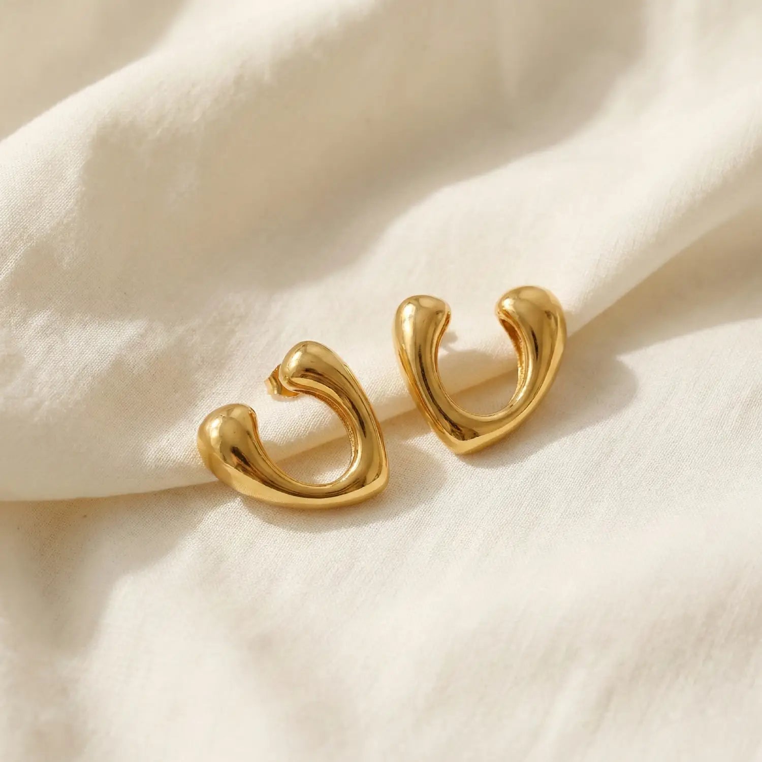 Gold earrings on a beige fabric background