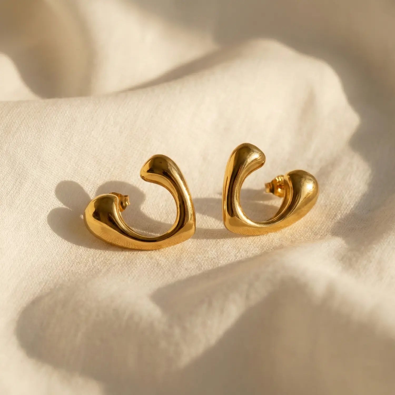 Pair of gold earrings on a beige fabric background