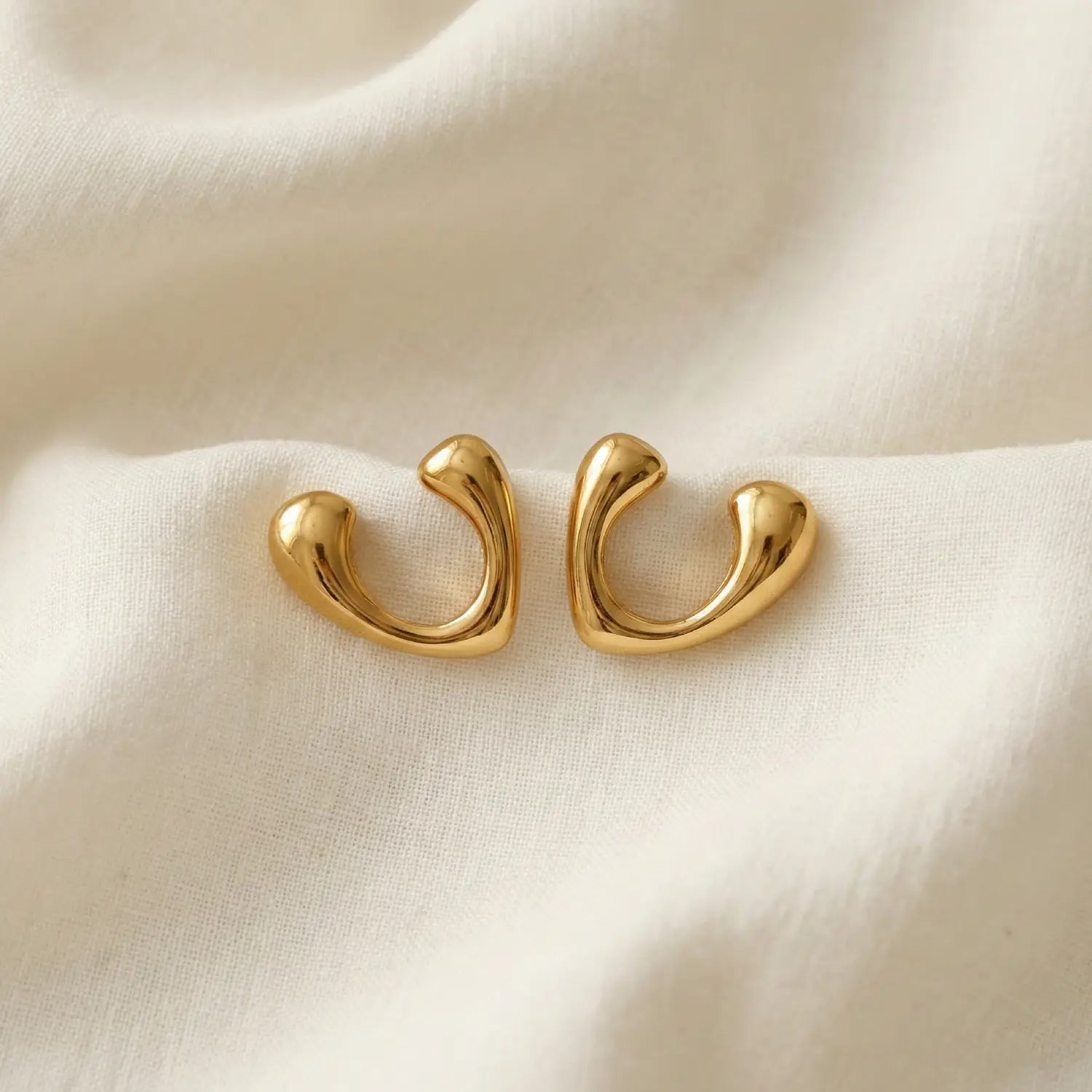 Gold hoop earrings on a beige fabric background
