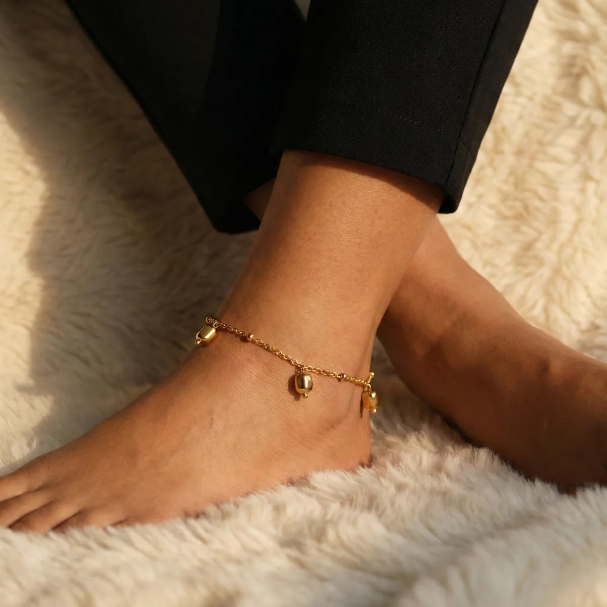Gold anklet on a foot with a soft white background